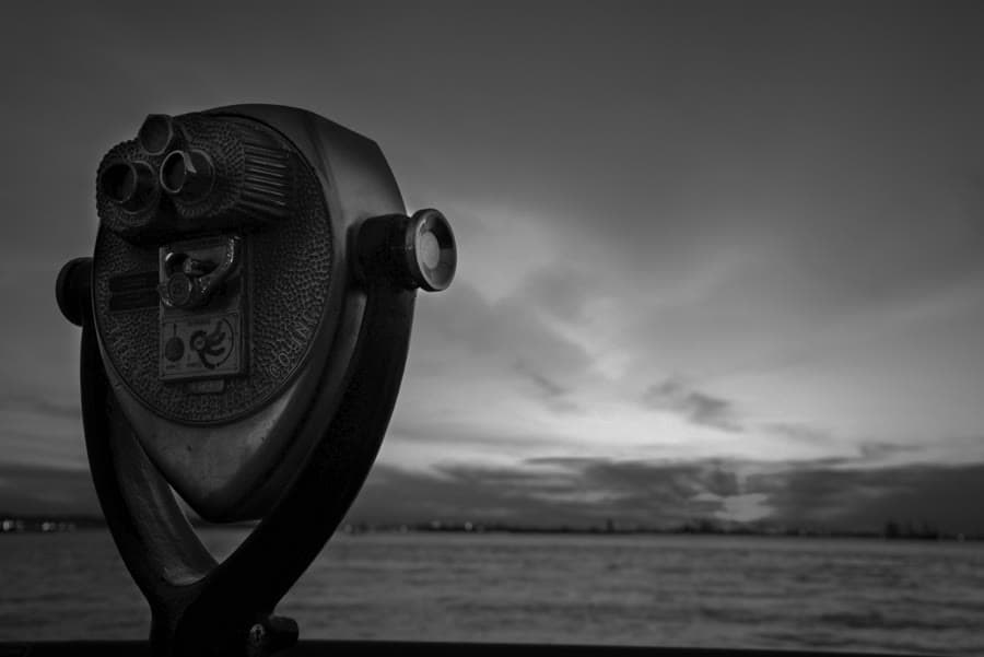 Coin-operated binoculars silhouetted against a stormy sky