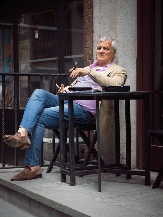 Man in sunglasses seated at a café table on a raised terrace
