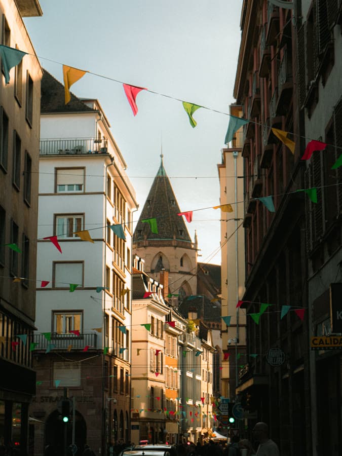 Narrow old-town street strung with colorful bunting under a church spire